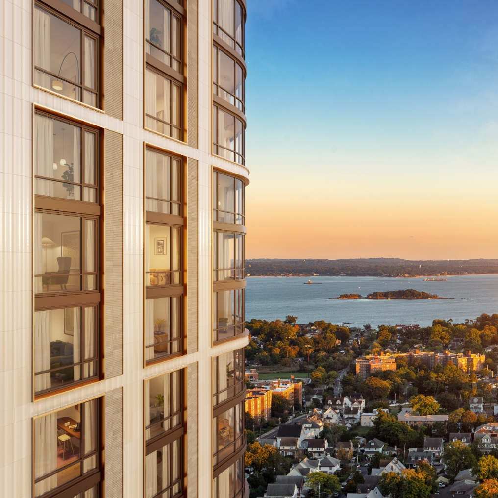 Exterior view of a modern 28-story luxury high rise tower with wraparound, floor-to-ceiling windows and views of the Long Island Sound.